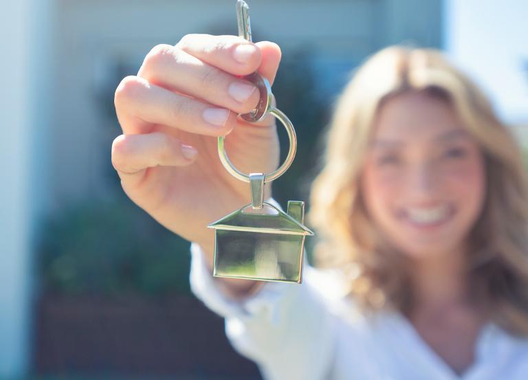 Kobieta z kluczem z brelokiem w kształcie domu